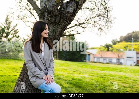 Junge Frau, die lächelnd die Natur genießt und sich im Freien entspannt Stockfoto