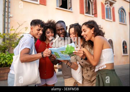 Verschiedene Gruppen von Freunden mit Stadtplan, die einen unterhaltsamen, unbeschwerten Moment während ihres urbanen Abenteuers genießen Stockfoto