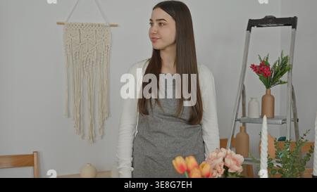 Blumenfrau, die an Blumen steht, Arme im Atelier zwischen Vasen und Leiter gekreuzt; ruhiges Vertrauen. Stockfoto