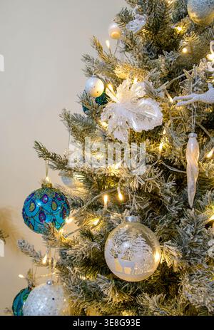Dekorierter Weihnachtsbaum mit blauen und weißen Kugeln und warmen Lichtern im gemütlichen Wohnzimmer während der festlichen Weihnachtszeit Stockfoto