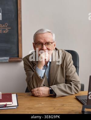 Vertikales Porträt eines Senior man sitzt am Schreibtisch für Bildungsleiter Stockfoto