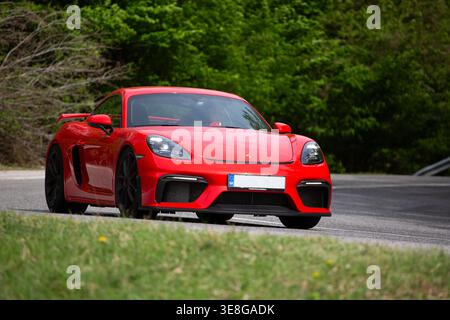 Dreiviertelansicht eines roten Porsche Cayman GT4 auf der Forststraße Stockfoto