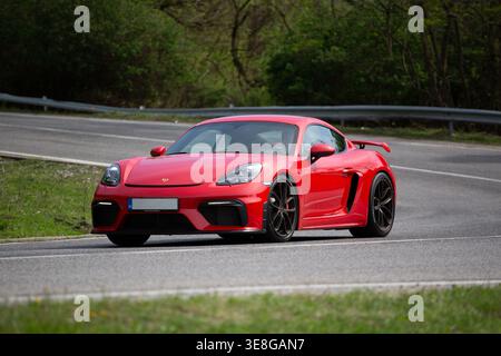 Dreiviertelansicht eines roten Porsche Cayman GT4 auf der Forststraße Stockfoto