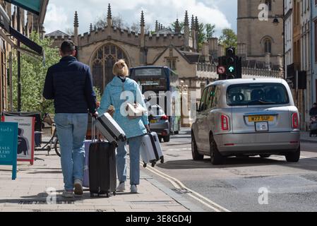 Ein Touristenpaar mit Gepäck, das die High Street in Oxford, Großbritannien, entlang läuft Stockfoto