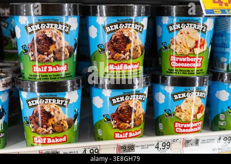 Ben & Jerrys halbgebackene Eisbecher-Behälter werden im Grocery Store Frozen Dessert Shelf im Retail Freezer Section ausgestellt Stockfoto