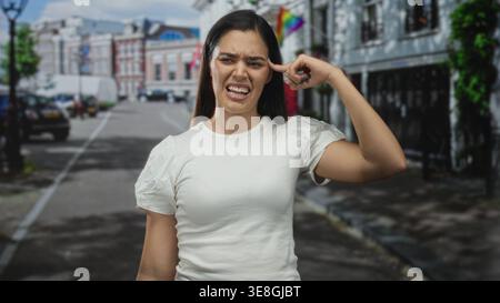 Die Frau zeigt mit dem Finger auf den Tempel auf der Straße der Stadt, während sie über Lärm und Verkehr grimmig ist; Frustration, Unglauben. Stockfoto