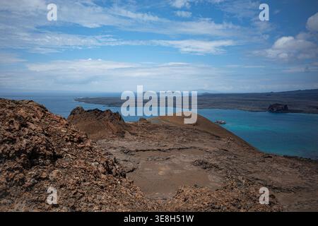Erhöhter Blick von Bartolome Island auf den Galapagos mit vulkanischem Gelände und türkisfarbenen Buchten unter blauem Himmel. Stockfoto