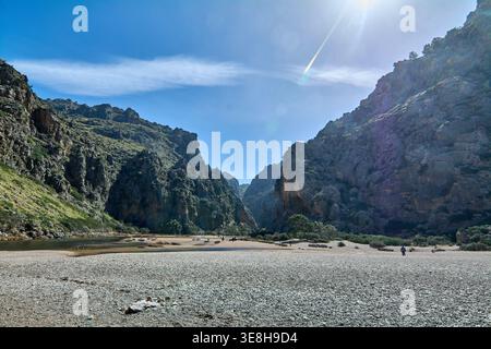 Spektakulärer Innenblick auf den Torrent de Pareis Canyon in Sa Calobra. Hoch aufragende Kalksteinklippen umgeben ein breites Kieselflüsschen unter einer hellen Sonne Stockfoto