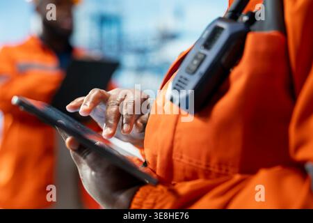 Nahaufnahme eines Profis auf Offshore-Plattform-Deck, der Derrick-Managementsysteme für eine effizientere Ölextraktion konfiguriert. Bohrkahn-Arbeiter, der Meeresbodenanalysen mit Tablet-Anwendung durchführt Stockfoto