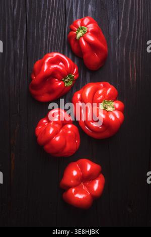 Blick von oben auf frische rote Paprika auf rustikaler Holzoberfläche. Frischer süßer Pfeffer Hintergrund, gesundes Lebensmittelkonzept Stockfoto