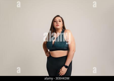 Selbstvertrauen und Wellness-Konzept. Schöne Frau in Übergröße mit stark kurvigem Körper posiert in Studio Activewear. Weibliches Modell fördert Selbstliebe, einschließlich Stockfoto