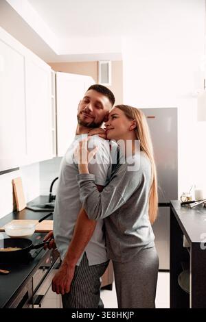 Zu Hause kochen, während man sich umarmt und die gemeinsame Zeit genießt. Vorstellung von Liebe, Lebensstil und Beziehungen. Stockfoto
