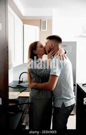 Romantischer Moment eines jungen Paares, das sich in der Küche küsst. Das Konzept von Liebe und Beziehung. Stockfoto