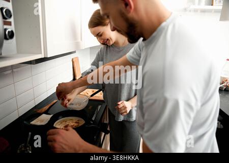 Ein junges Paar kocht Pfannkuchen in der Küche. Lebensstil-Konzept. Stockfoto