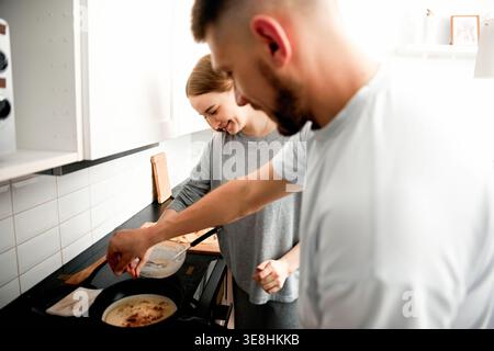 Hände von Paaren, die zusammen Pfannkuchen vorbereiten. Konzept des morgendlichen Lebensstils und Kochens. Stockfoto