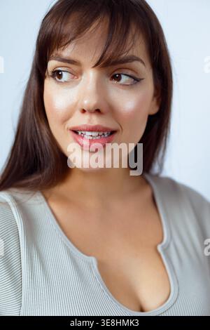 Eine Frau lächelt hell, während sie für ein Porträt posiert. Ihr Make-up verbessert ihre Gesichtszüge und sie zeigt eine fröhliche Emotion in einer lebendigen Umgebung Stockfoto