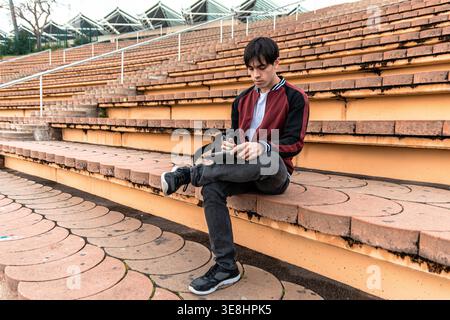 Junger Mann, der mit Tablette auf Stadiontreppen lernt Stockfoto