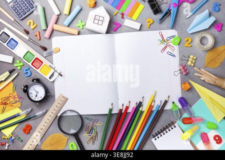 Set mit Schulzubehör und Schreibwaren mit offenem Notizbuch auf grauer Tischansicht. Bildung, Lernen und Schulanfang Stockfoto