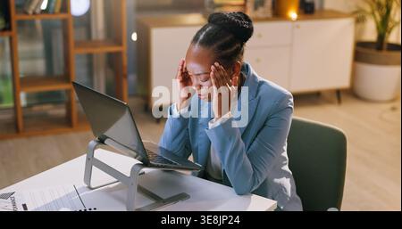 Schwarze Frau, Kopfschmerzen und Laptop nachts im Büro wegen Störungen, Nachrichtenfehlern und Überlastung. Stress, Journalist und Migräne mit pc, Texterstellung scheitern Stockfoto