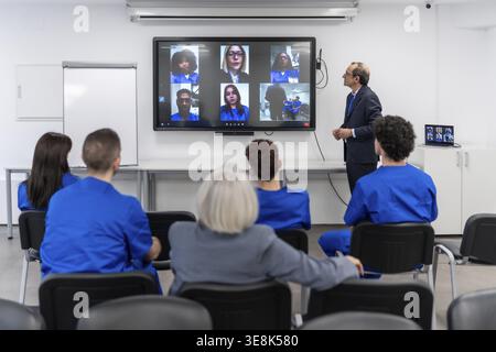 Medizinische Fachkräfte und Studenten nehmen an einer persönlichen und Remote-Videokonferenz teil, um mehr über medizinische Ausbildung und Beruf zu erfahren Stockfoto