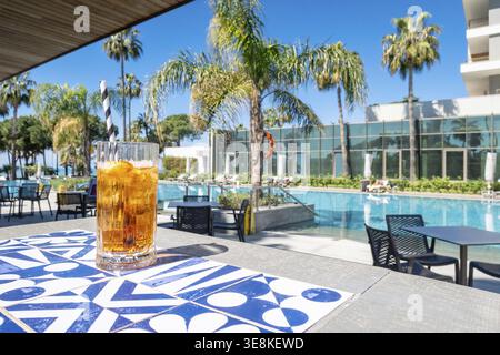 Frischer alkoholischer Cocktail mit Eis im Glas am Swimmingpool. Hartes starkes Getränk bei Sonnenlicht mit Palmen. Konzept Sommer Luxus Urlaub und Reise Stockfoto
