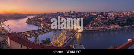 Ein filmisches XPan-Panoramafoto, das während des Sonnenuntergangs aufgenommen wurde, mit der beleuchteten Brücke Dom Luís i über den Fluss Douro mit der Skyline o Stockfoto
