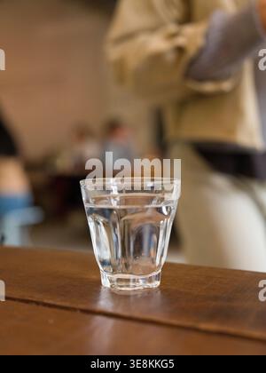Flacher, flacher Bagel mit geflochtenem hinterem Holztisch aus weißer Platte. Dieses Bild zeigt einen einfarbigen Bagel, geflochtene Rückseite, niedrigen Winkel. Nahaufnahme von frisch gebackenem Ar Stockfoto