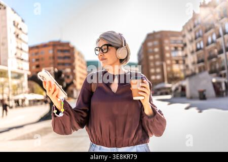 Moderne Frau, die in der Stadt läuft und Musik hört Stockfoto
