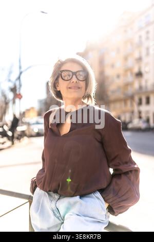 Selbstbewusste reife Frau, die sonnigen urbanen Lebensstil im Freien genießt Stockfoto