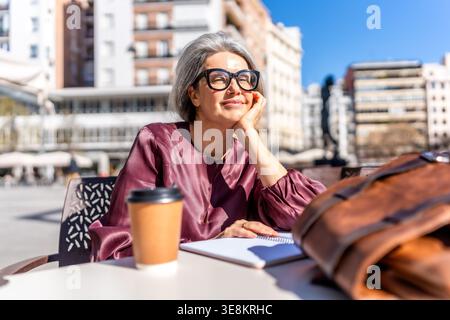 Seniorin genießt entspannende Momente im Café im Freien Stockfoto