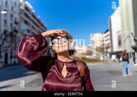 Reife Frau genießt Sonne und Musik in der Stadt Stockfoto