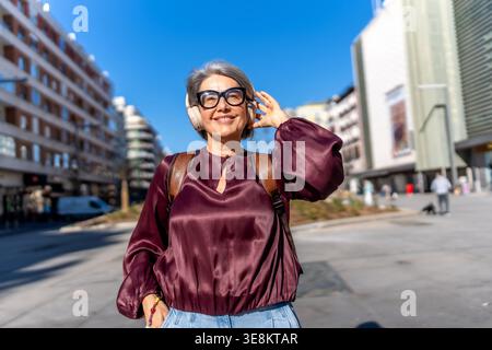 Glückliche Frau, die Musik auf der städtischen Straße hört Stockfoto