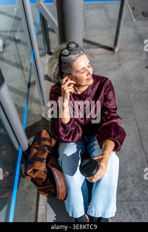 Frau genießt Kaffeepause im Sonnenlicht der Stadt Stockfoto