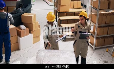 Lagerarbeiter planen Versand und Verteilung im Lagerraum und analysieren die Liste des Lagerbestands. Lagerraumleiter, der Industriegüter in Kartons organisiert, kleine Unternehmen. Stockfoto