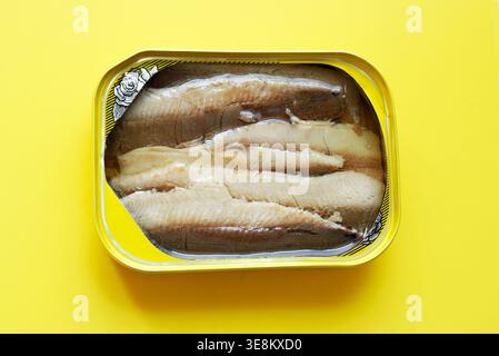 Nahaufnahme einer offenen Dose Sardinen mit Fischfilets in Öl, verzehrfertig.Ein gesunder Snack und Zutat für die mediterrane Küche, gelber Hintergrund Stockfoto