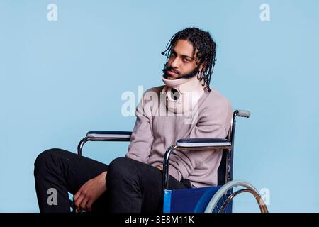 Erschöpfter verletzter arabischer Mann mit Nackenstütze und im Rollstuhl sitzend, während er sich nach einem körperlichen Trauma erholt. Müde Person im Halswirbelkragen in ärztlicher Behandlung nach Unfall Stockfoto
