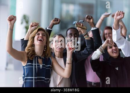 Geschäftsteam feiert gemeinsam in einem vielfältigen Unternehmensbüro mit freudiger Teamarbeit und Einheit Erfolg Stockfoto