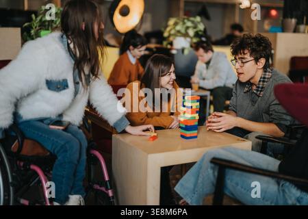 Schüler lachen und spielen gemeinsam ein Blockspiel in einem gemütlichen Campus-Café Stockfoto