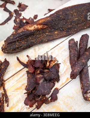 Detaillierte Nahaufnahme verschiedener Biltong-Schnitte und trockener Würmer, die eine abstrakte Lebensmittelzusammensetzung schaffen. Reichhaltige Texturen und Gewürze unterstreichen den traditionellen Südpazifik Stockfoto
