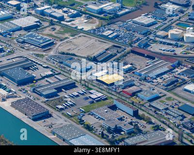 Aus der Vogelperspektive eines weitläufigen Industriegebiets, in dem sich die starke Geometrie der Lagerhäuser und Fabriken mit dem sich schlängelnden Kanal Sausheim, Grand, abhebt Stockfoto