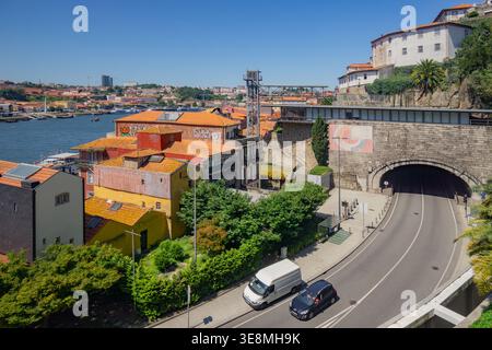 Blick aus der Vogelperspektive auf die Terrakotta-Dächer, die in Richtung des Flusses Douro fallen, gegenüber der modernen Infrastruktur und historischen Architektur, Porto, P Stockfoto