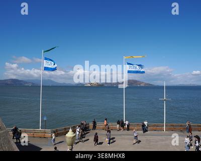 San Francisco, USA - 3. Oktober 2025 - Ein Blick auf die Bucht von San Francisco vom Pier 39, mit Fahnen, die im Wind winken und Touristen, die die d Stockfoto