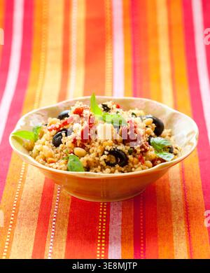 mediterraner Couscous-Salat mit getrockneten Tomaten, Feta, Oliven und Basilikum Stockfoto