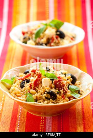 mediterraner Couscous-Salat mit getrockneten Tomaten, Feta, Oliven und Basilikum Stockfoto