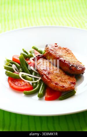 Gegrilltes Schweinefleisch mit grünen Bohnen und Tomaten Stockfoto