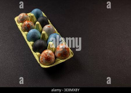 Eier in einem Eierkarton aus Pappe mit einer einzigartigen Mischung aus blauen, schwarzen und rostfarbenen Marmortexturen, die Themen des Raumes und künstlerische des widerspiegeln Stockfoto