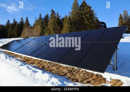 Solarpaneele, die auf einem Rahmen neben einer abgelegenen Berghütte in Polen montiert sind. Photovoltaik-Energieerzeugung im Winter in den Beskiden in Polen. Stockfoto