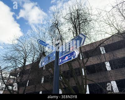 Manchester, Großbritannien - 22. Februar 2026: Städtische Straßenschilder in Manchester, Großbritannien, die auf kulturelle Attraktionen und Fußgängerrouten unter bewölktem Himmel hinweisen Stockfoto