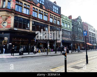 Manchester, Großbritannien - 22. Februar 2026: Geschäftige Straßenszene in Manchester mit farbenfrohen viktorianischen Geschäften, Einkaufsmöglichkeiten und urbaner Atmosphäre Stockfoto