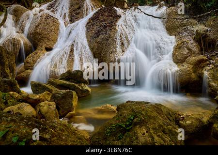Ruhiger Wasserfall, der über Moosfelsen in einem üppigen Wald fließt Stockfoto